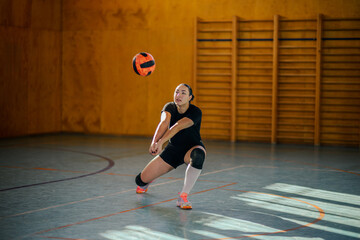 Woman player libero of a volleyball team bumping a ball in an indoor court