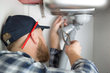 view of a plumber fixing a sink pipes