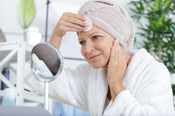 senior woman towel on head holding a cotton pad