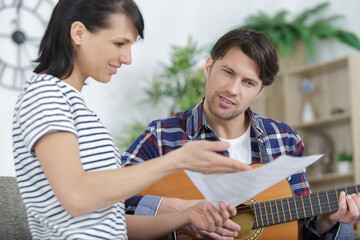 young beautiful couple resting at home and playing guitar