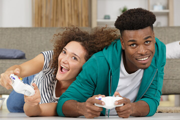 smiling couple lying on the floor playing video games