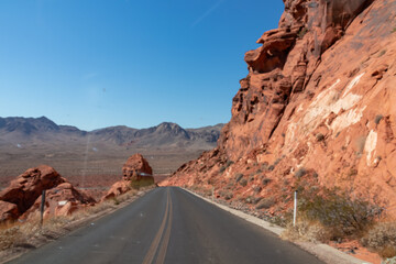 Panoramic view of endless winding empty Mouse tank road in Valley of Fire State Park through canyons of red Aztec Sandstone Rock formations and desert vegetation in Mojave desert, Overton, Nevada, USA