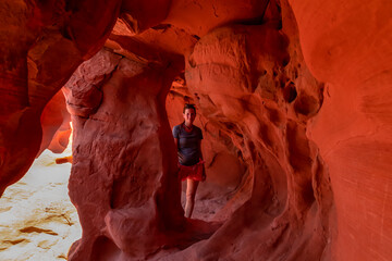 Woman standing in the fire cave and Windstone Arch in Valley of Fire State Park, Nevada, USA. Long,...