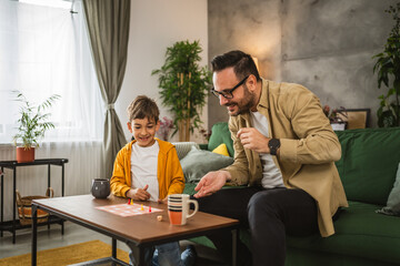 Father and son play board game together at home