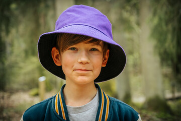 Portrait of a young boy in a hat. Close-up.Portrait of a smiling boy in a hat in the forest. © Emvats