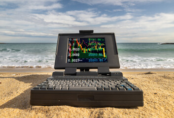 laptop computer system by the sea with trading data on screen