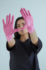 A beautiful woman in a black suit with pink gloves.
