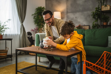 Father show son how to save money at piggy bank at home