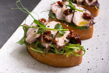 bruschetta with veal and sun-dried tomatoes, pesto sauce, garnished with peas microgreens