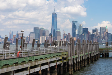 A wooden pier on the Hudson River with captivating New York urban skyline with striking and modern...