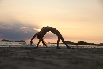 Silhouette workout woman stretching arms and legs exercising during sunset at the beach, Yoga...