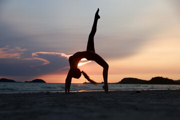Silhouette workout woman stretching arms and legs exercising during sunset at the beach, Yoga concept