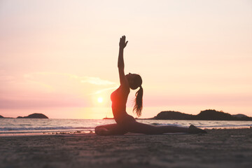 Silhouette workout woman stretching arms and legs exercising during sunset at the beach, Yoga...