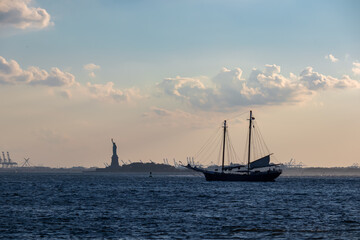 A sailing boat crossing the bay of New York with the view on Statue of Liberty in the back. There...