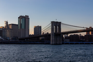 Iconic Brooklyn Bridge connecting New York City's urban landscape seen from below. There are a lot...