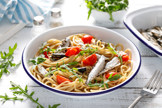 Whole grain pasta with sardines, tomato and arugula. Italian Sicilian cuisine.