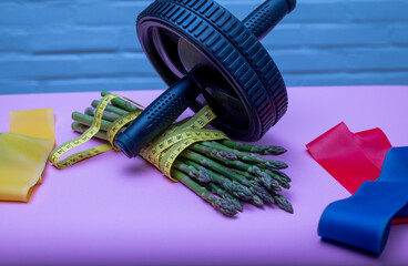 Sports accessories with green asparagus on a lilac background with measuring tape.