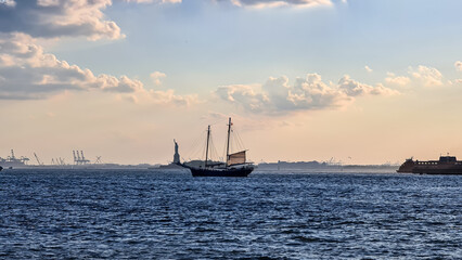 A sailing boat crossing the bay of New York with the view on Statue of Liberty in the back. There...