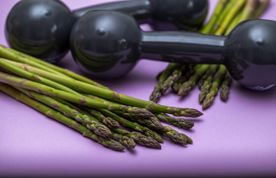 Dark grey dumbels with fresh green asparagus. 
