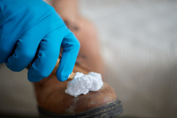 Applying cleaning foam from the bottle to white leather women's sneakers. Care for leather shoes,...