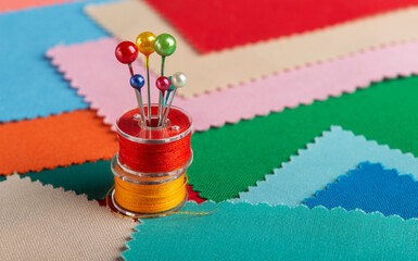 sewing kit. bobbins with colored threads Background of colored scraps of fabric.