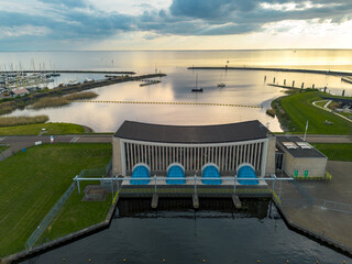 Aerial drone view of lock complex in Frisian city of Stavoren. Large pumping station beside bridge and sluice and historic town with canal, lake, and waterways