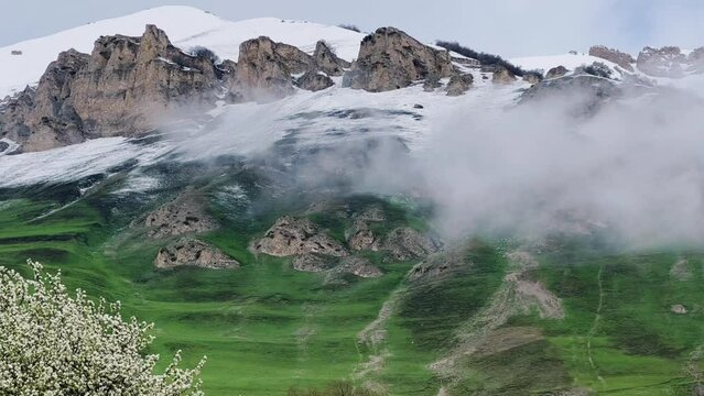 A trail in the green valley of the Karmadon gorge overlooking the Kolka glacier. The Main Caucasian Ridge. Summer view of the Karmadon gorge. A mountain valley after the collapse of rocks and ice. 4К