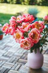 A pink vase with vertical ridges holding a beautiful bouquet of vibrant pink peonies