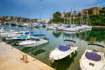 Obraz premium The Porto Cristo harbor in Mallorca offers a serene scene with boats gently anchored amidst a backdrop of coastal buildings