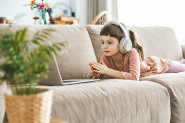 A cute little girl, watching a laptop screen, fully absorbed in her digital world. Concept: technology-infused relaxation, online education, technological entertainment