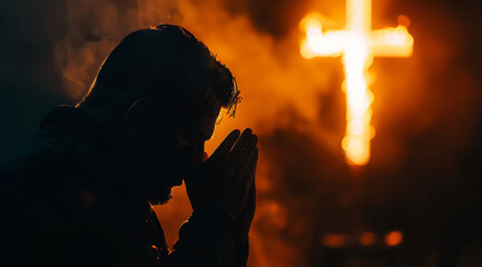 Devout faithful christian prays in front of the cross that is burning