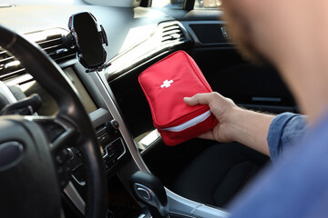 Man with first aid kit inside car, closeup