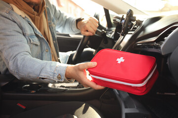 Fototapeta premium Man with first aid kit inside car, closeup