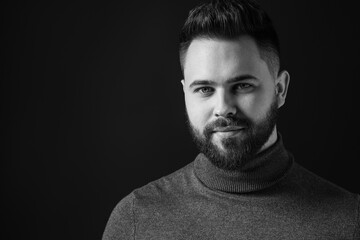 Portrait of handsome bearded man on dark background, space for text. Black and white effect