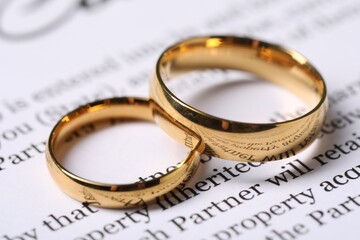 Marriage contract and gold rings on table, closeup