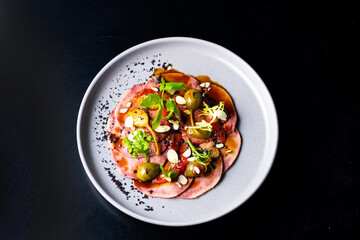 Beef tongue with sauce and vegetables on a white plate