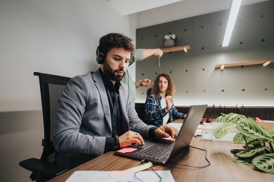 A team of diverse colleagues in a well-lit office engage seriously and playfully in a brainstorming session, utilizing modern technology and creative tools.