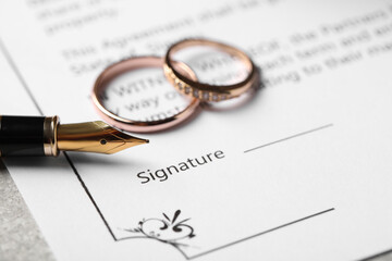 Marriage contract, fountain pen and wedding rings on table, closeup