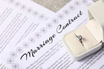Marriage contract and ring with gemstone on table