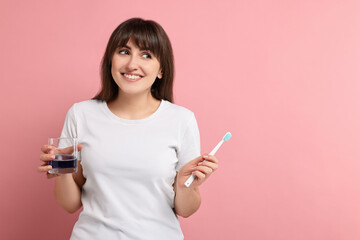Young woman with mouthwash and toothbrush on pink background, space for text