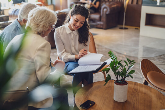 A hotel or travel agency representative is talking with a senior tourist couple offering various tourist services