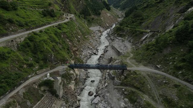 Aerial Drone shot of a black car crossing a river in the mountains of Uttarakhand. 