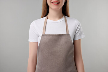 Woman wearing kitchen apron on grey background, closeup. Mockup for design