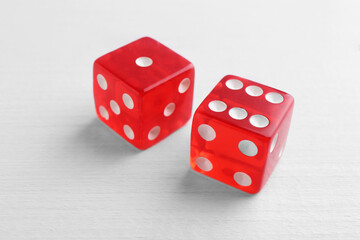 Two red game dices on white wooden table, closeup