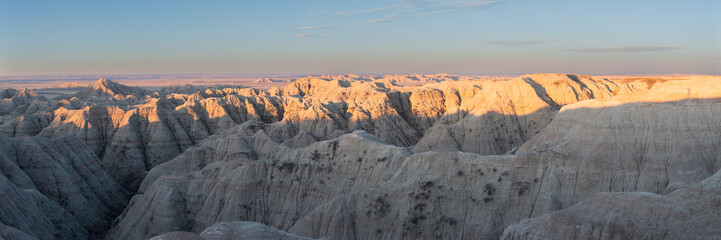Panoramic Views of the golden rays of sun touching the cliffs and canyons of South Dakota's Badlands National Park in spring at sunrise. 