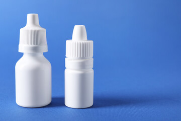 Bottles of medical drops on blue background, space for text