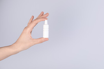 Woman with bottle of medical drops on gray background, closeup