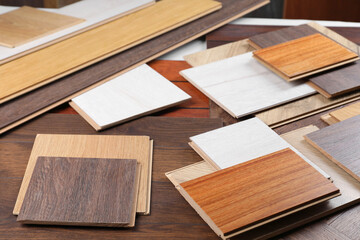 Many different samples of wooden flooring on table