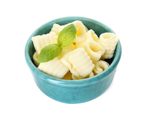 Tasty butter curls and basil leaves in bowl isolated on white