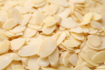 Fresh almond flakes as background, closeup view